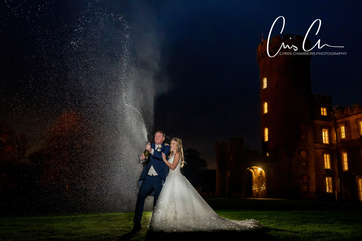 Bride and groom spray champagne in the evening of their wedding day.  Swinton Park Wedding Photograph