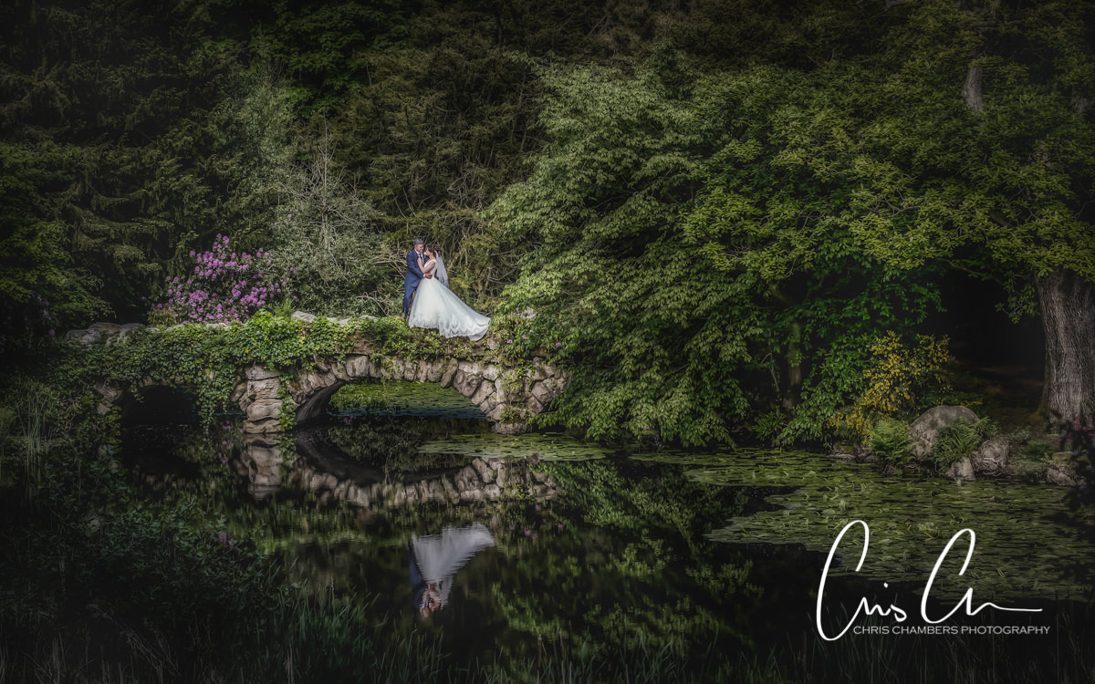 Bride and groom in the woods and reflected on a bridge at Swinton Park, north Yorkshire wedding venue. 
