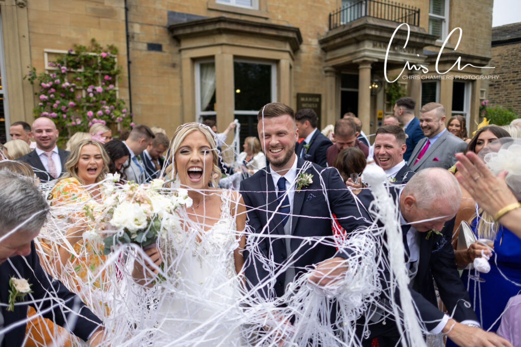 Bride and groom laughing amid streamers at Manor House Lindley 