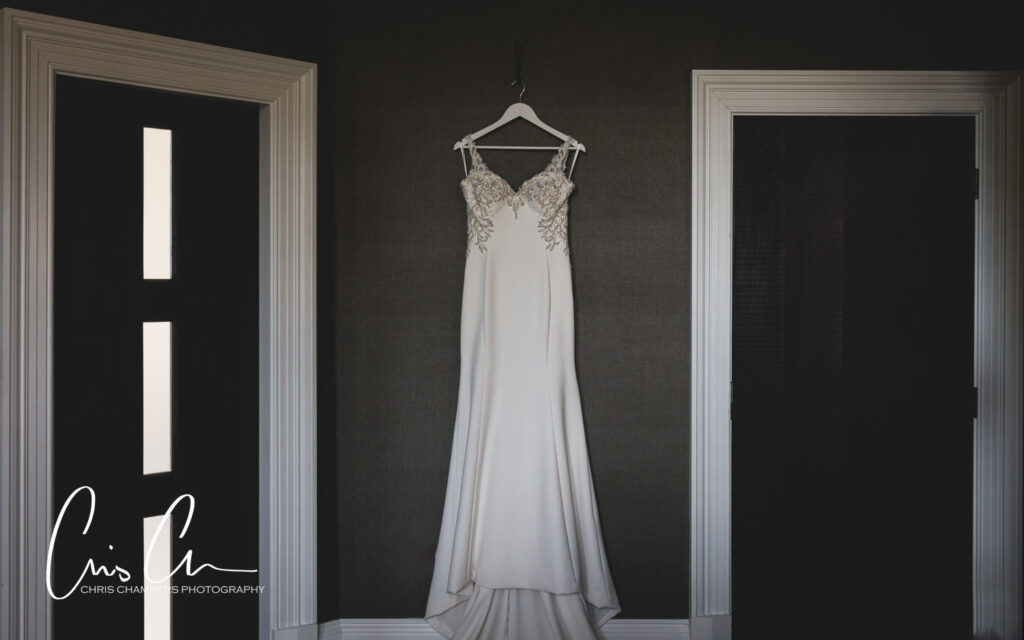 Elegant wedding dress hanging between open doors.