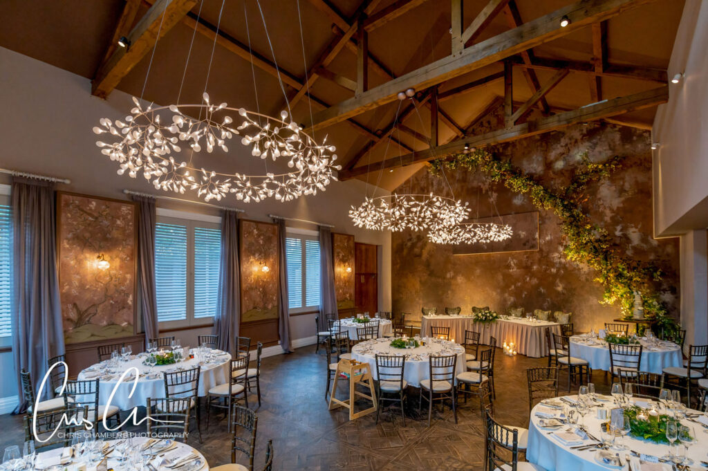 Elegant indoor wedding reception venue with chandeliers and foliage.