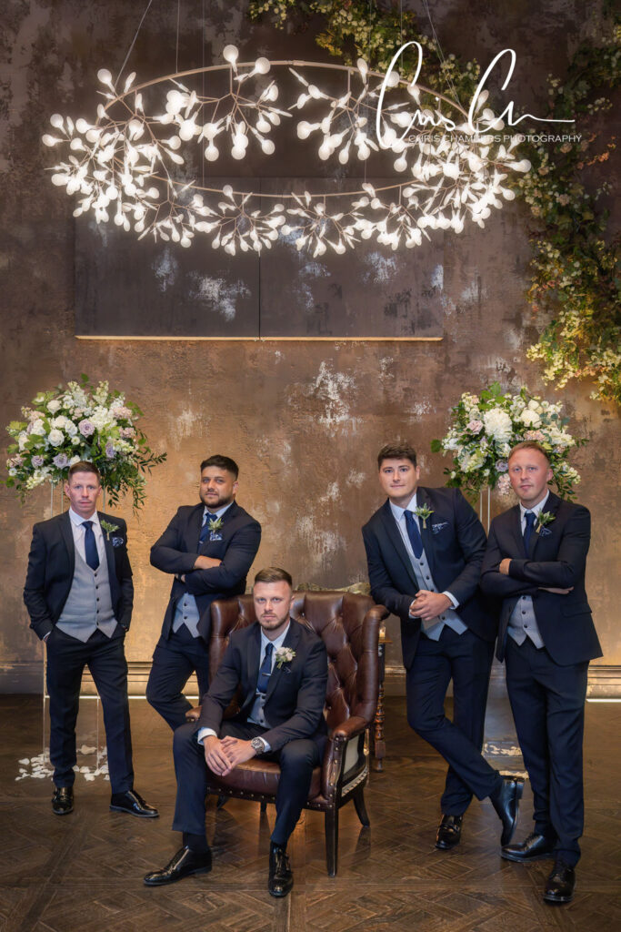 Groomsmen in suits posing elegantly at wedding venue.