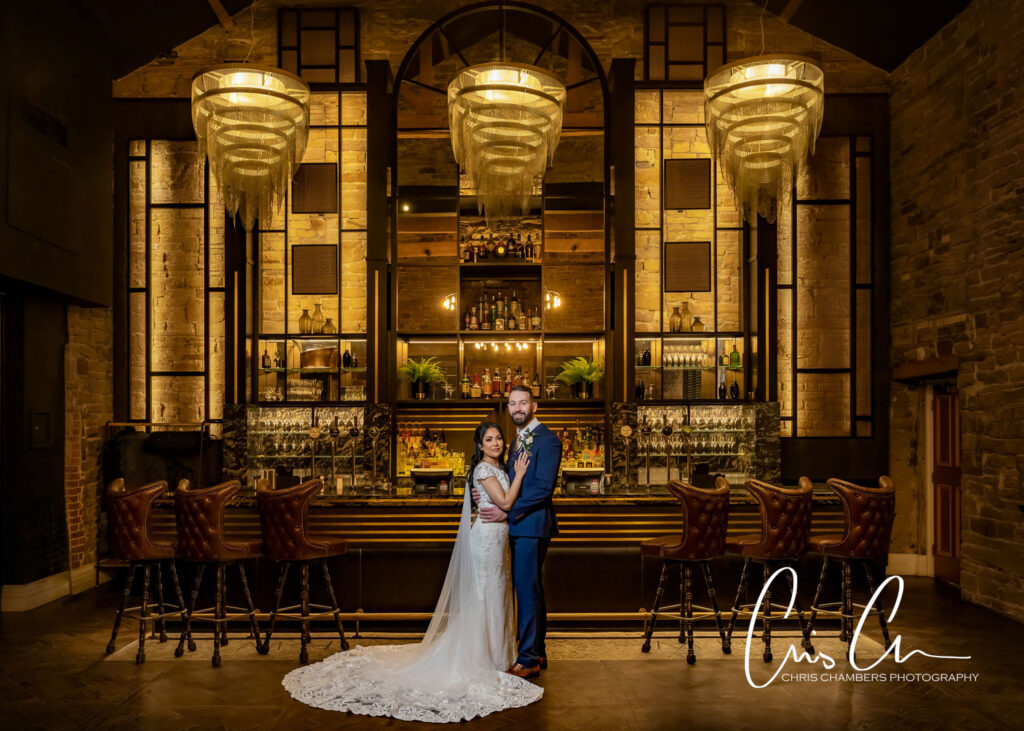 Wedding couple posing at elegant bar with chandeliers. Manor House Lindley.