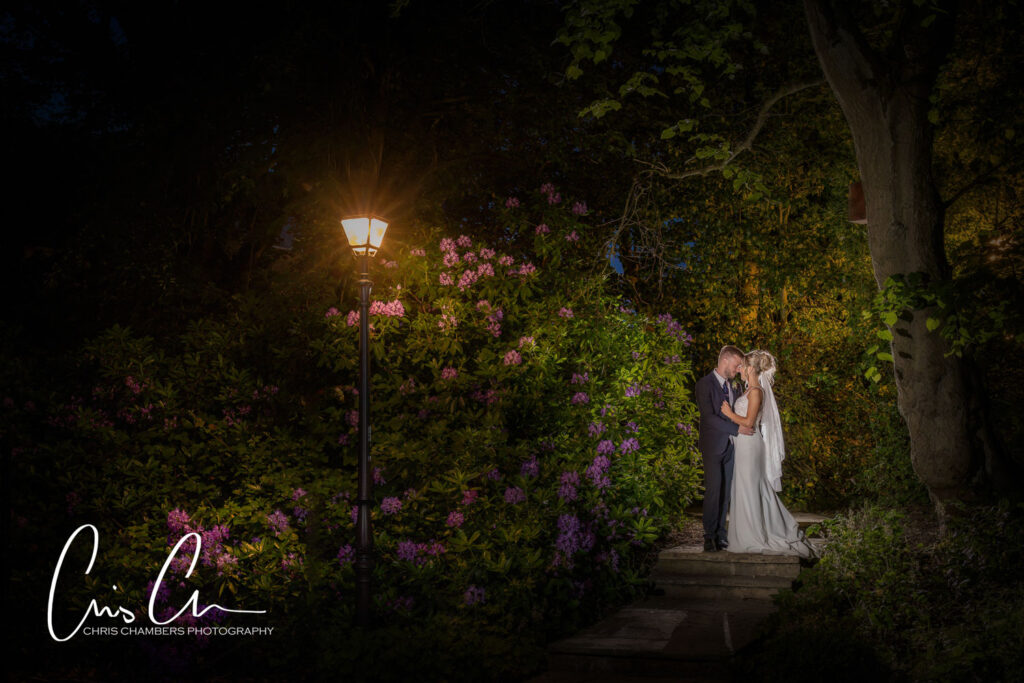 Couple kissing in illuminated night garden wedding.
