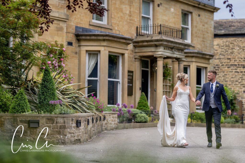Bride and groom walking hand in hand outside Manor House