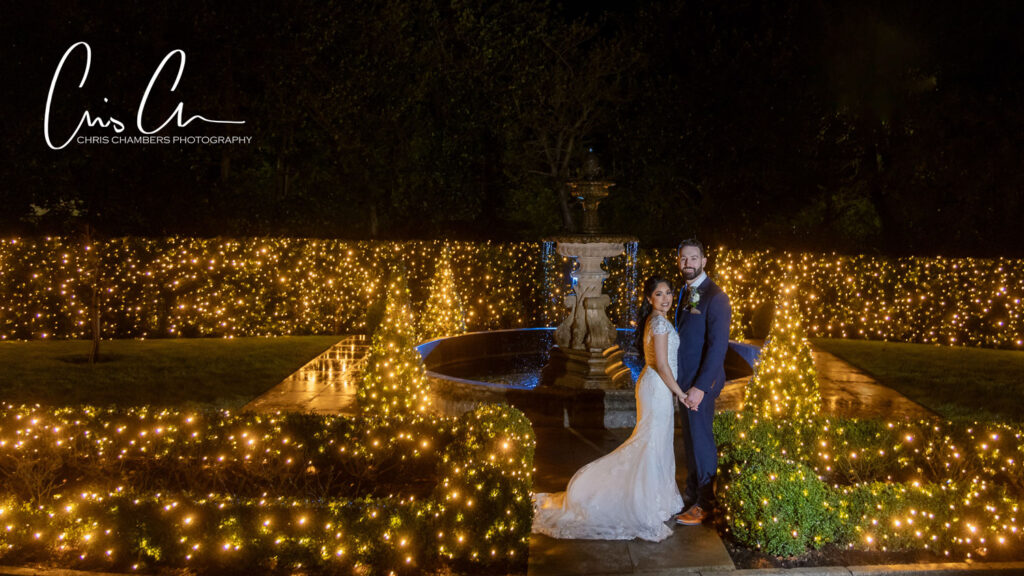 Manor House grounds, Couple by illuminated fountain at night wedding.