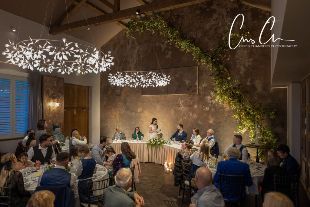 Elegant wedding reception with guests and decorative lighting.