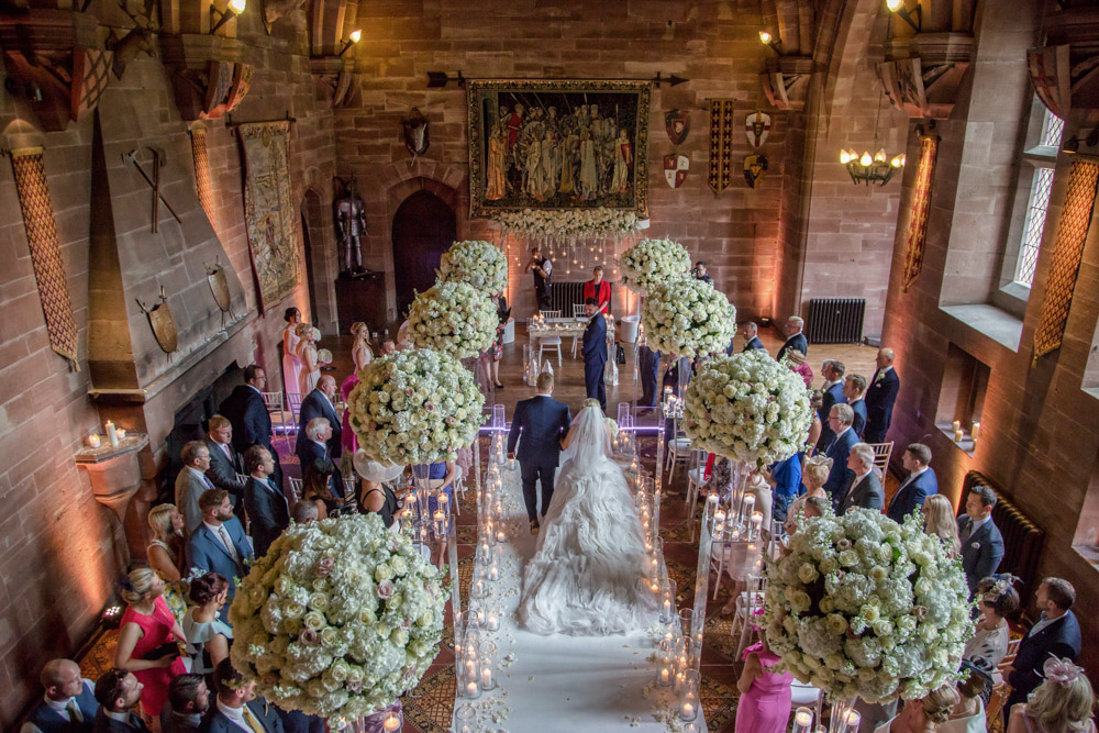 The bride and father make their entrance to the wedding ceremony in the Great Hall at Peckforton Castle, Cheshire