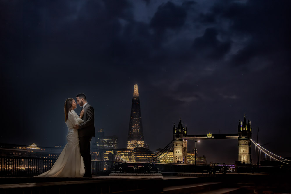 Couple at night with London skyline and Tower Bridge. London wedding photograph