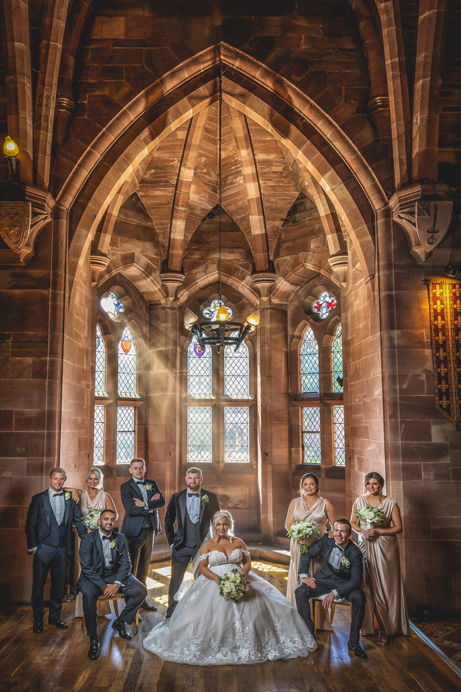 Bridal party group photograph in the Great Hall at Peckforton Castle.