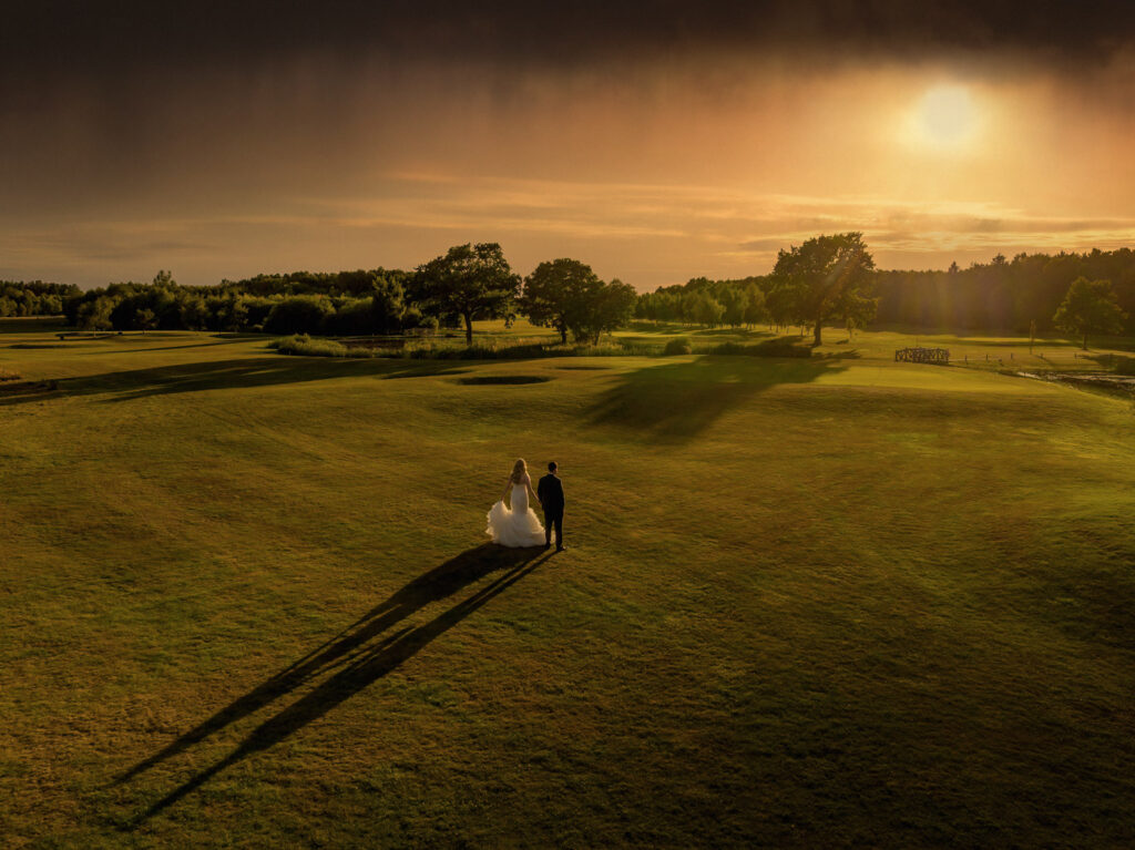 Bride and groom walk towards the sunset at Sandburn hall near York. Chris Chambers Yorkshire wedding photographer