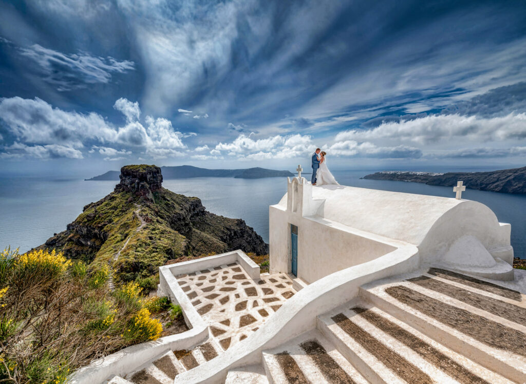 Couple on scenic cliffside with ocean view in Santorini.