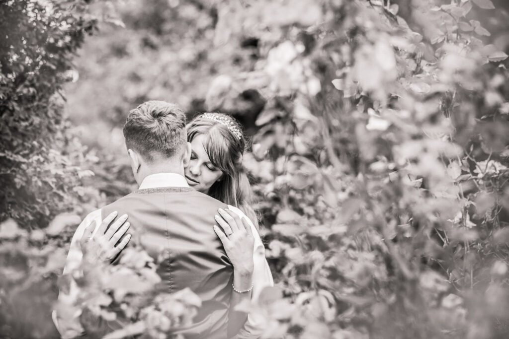 Couple embracing surrounded by nature in black and white.