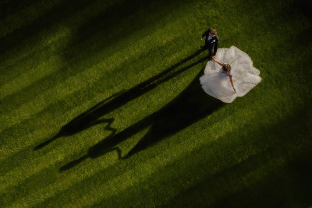 Bride and groom with long shadows on grass. Chris Chambers Yorkshire wedding photographer