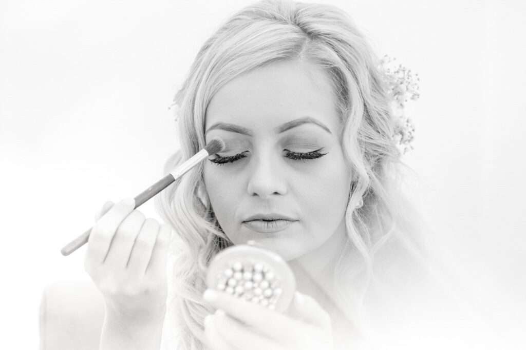 Bridal makeup application in black and white.