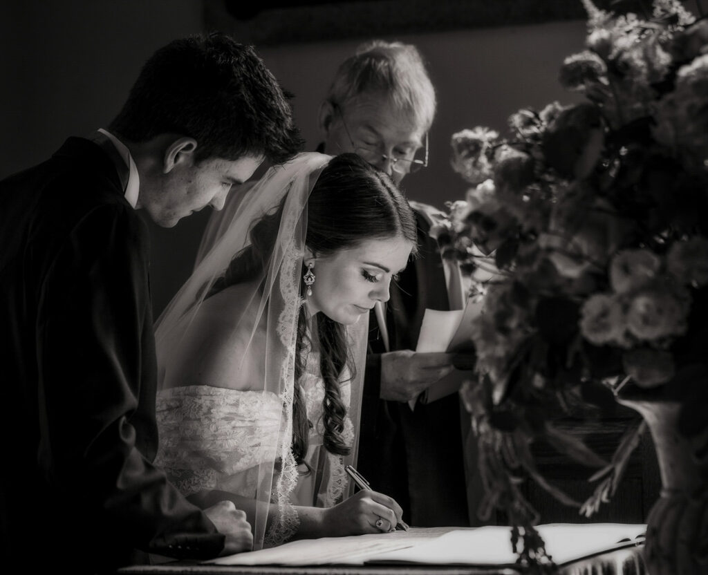 Bride and groom signing marriage certificate at wedding.