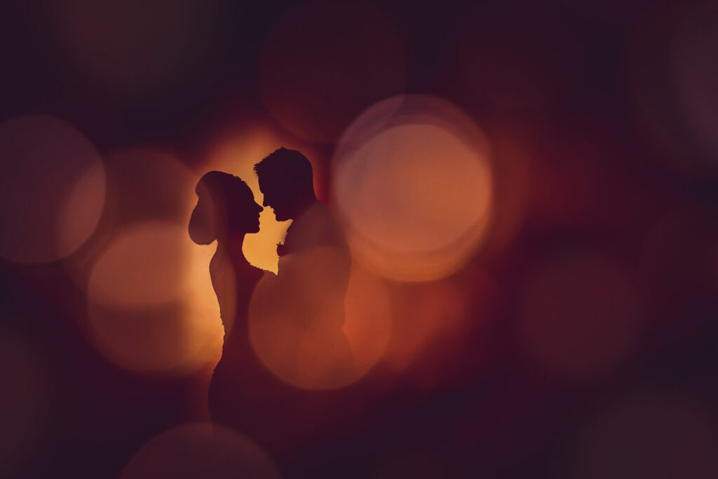Silhouetted couple with bokeh lights background. Chris Chambers Yorkshire wedding photographer