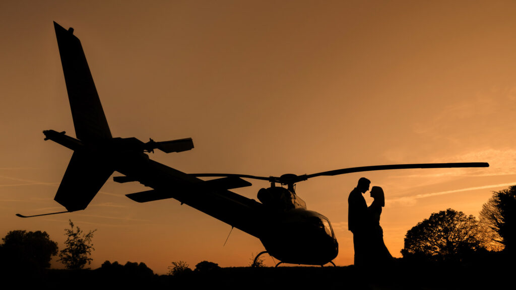 Silhouette of couple and helicopter at sunset. Hazlewood Castle helicopter wedding photo