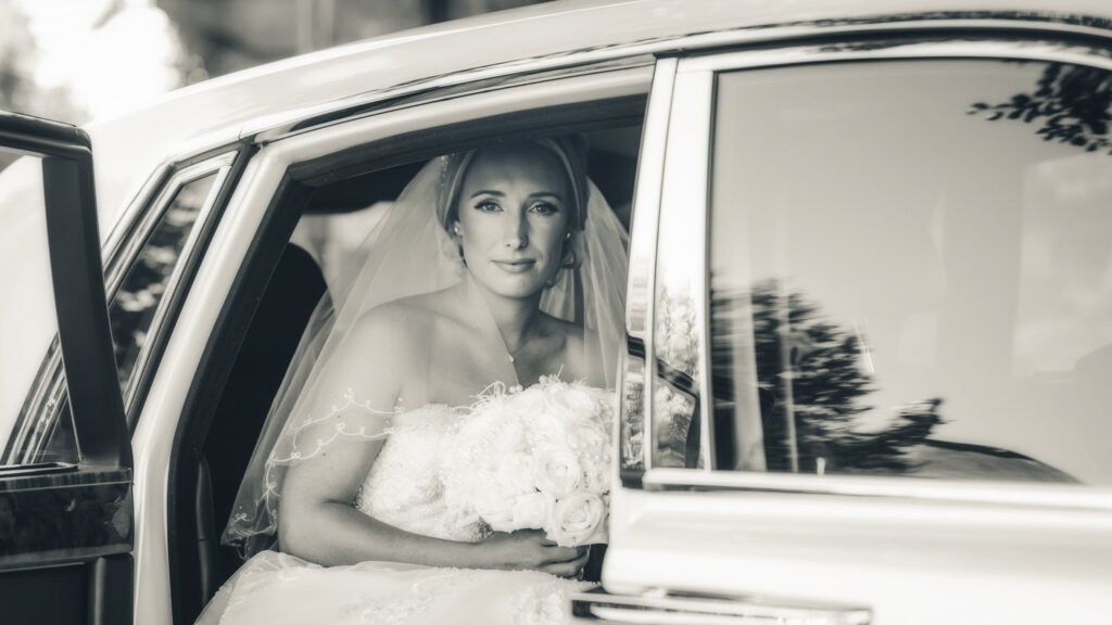 Bride sitting in car holding bouquet. Chris Chambers Yorkshire wedding photographer