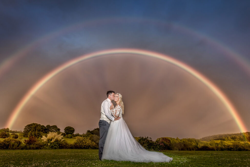 Bride and groom kissing under double rainbow. Chris Chambers Yorkshire wedding photographer