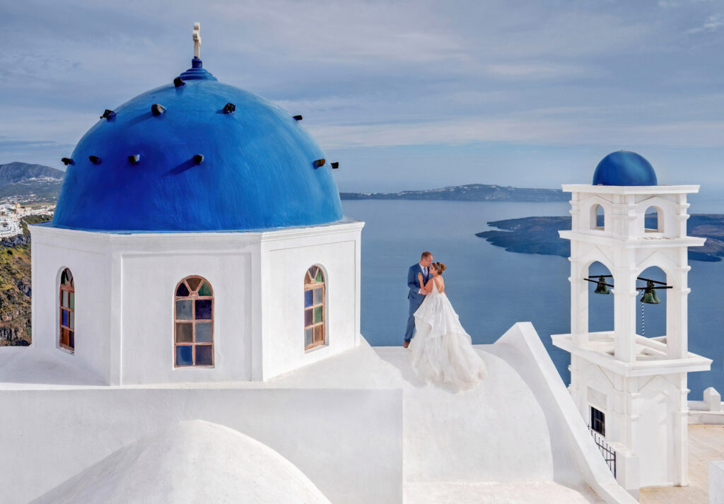 bride and groom kissing by blue dome, Santorini Greece.