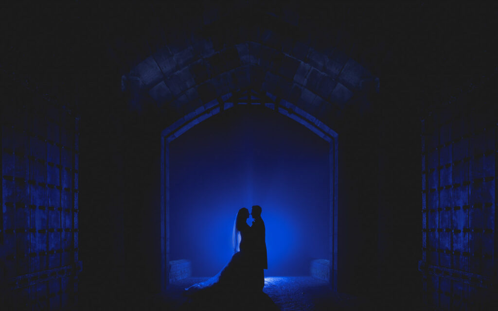 Couple silhouette in blue-lit gatehouse at Peckforton Castle