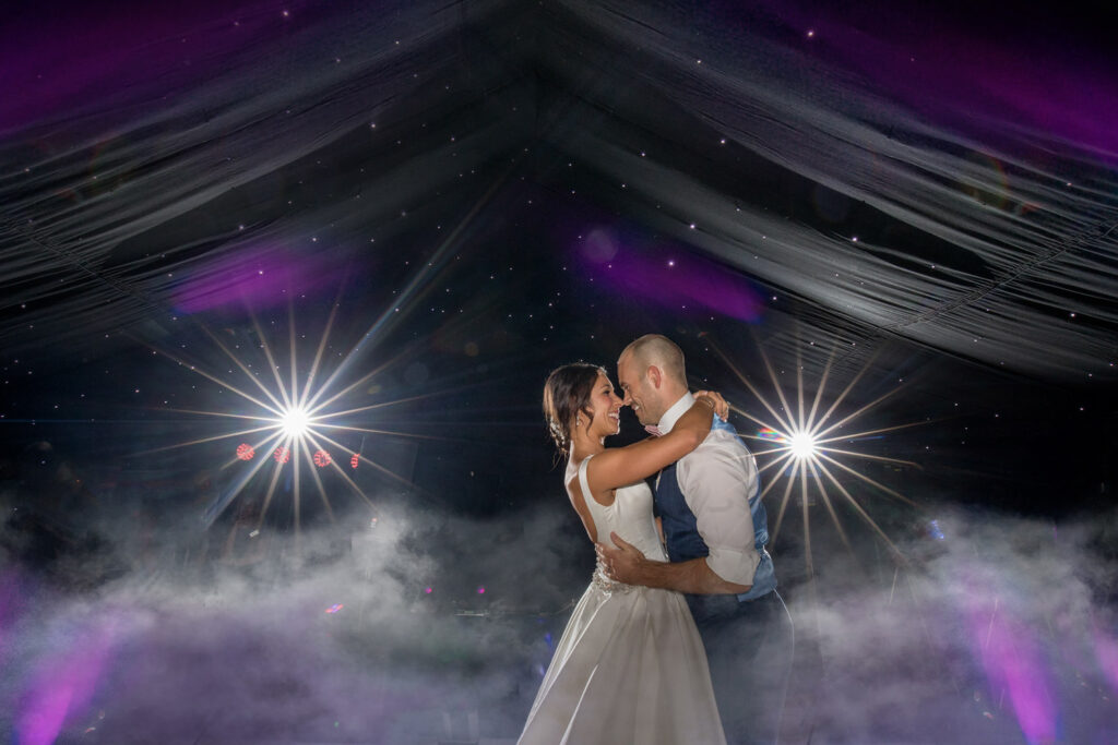 Couple dancing at wedding with lights and smoke effects.