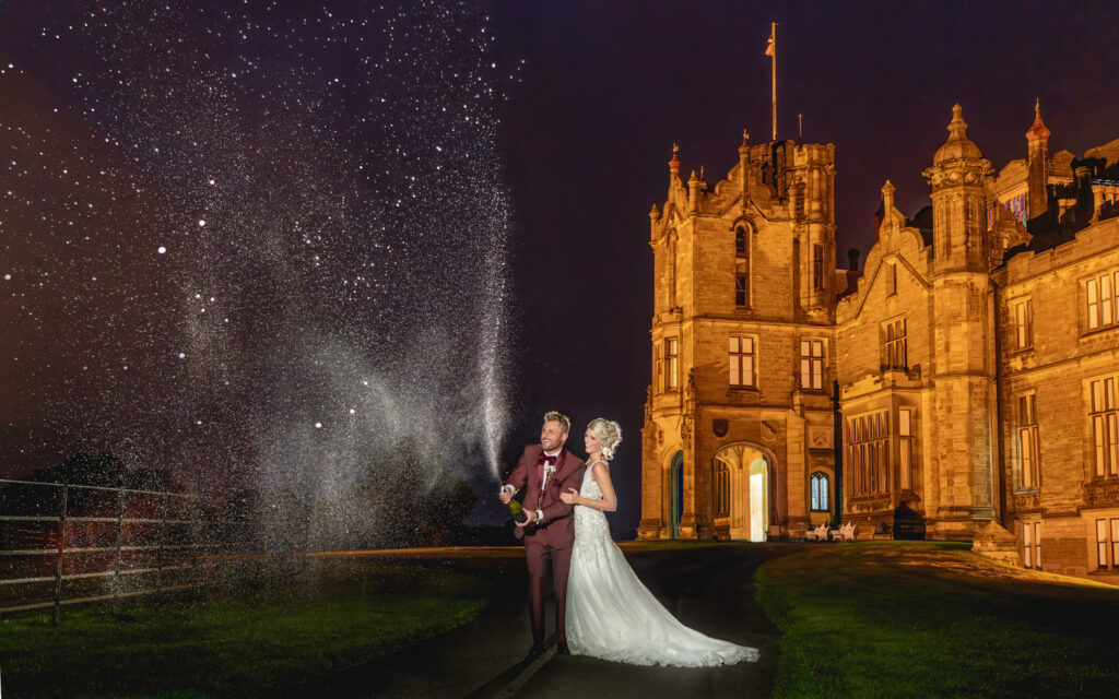 Couple celebrating with champagne at night by Allerton castle.