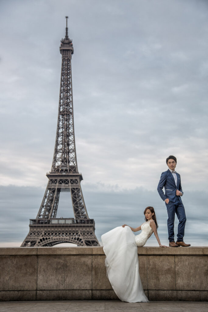 Couple posing with Eiffel Tower background in wedding attire.