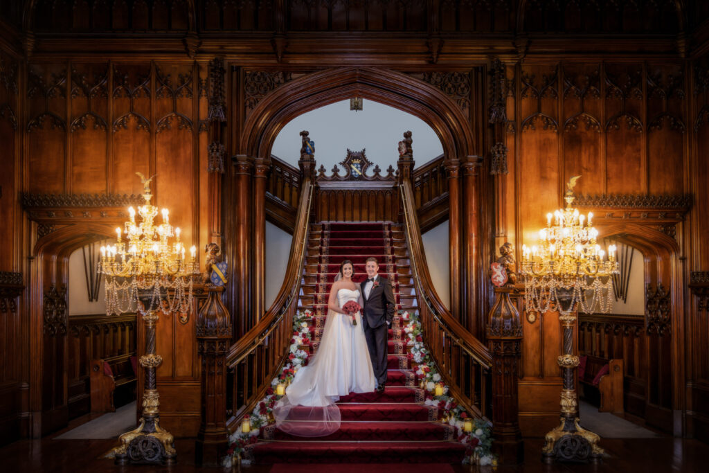 Couple posing on grand staircase at wedding venue.