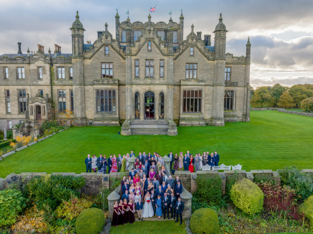 Wedding guests in front of historic mansion.