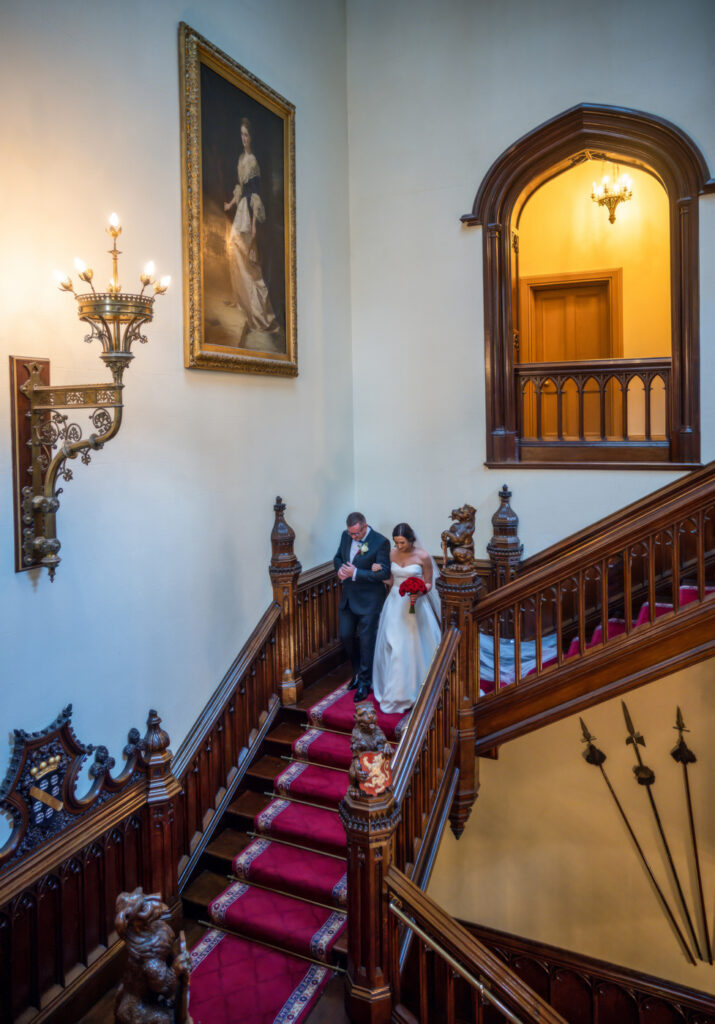 A bride and groom standing on the stairs of an ornate building. Wedding ceremony in the Great Hall at Allerton Castle. Wedding Photography from Chris Chambers