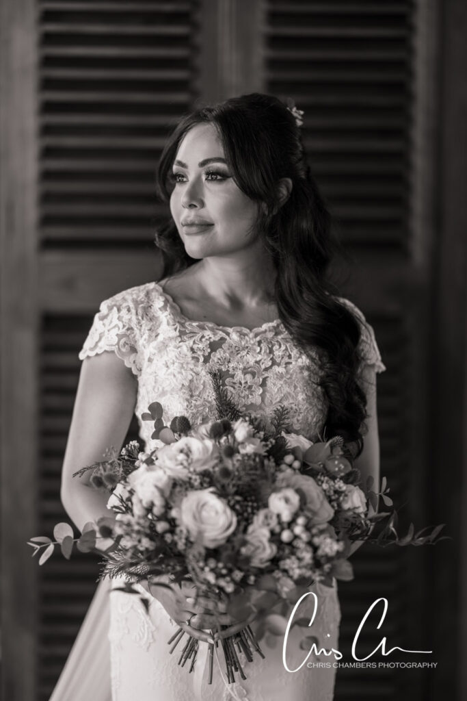 Bride in elegant dress holding bouquet, black and white photo. Manor House Lindley weddings.
