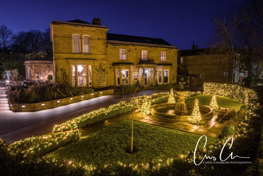 Illuminated house and garden with festive lights at dusk. Manor House Lindley weddings.