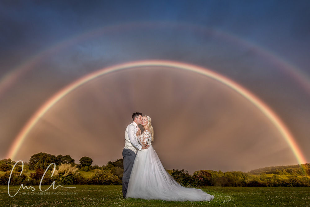 Bride and groom with a double rainbow at a wedding