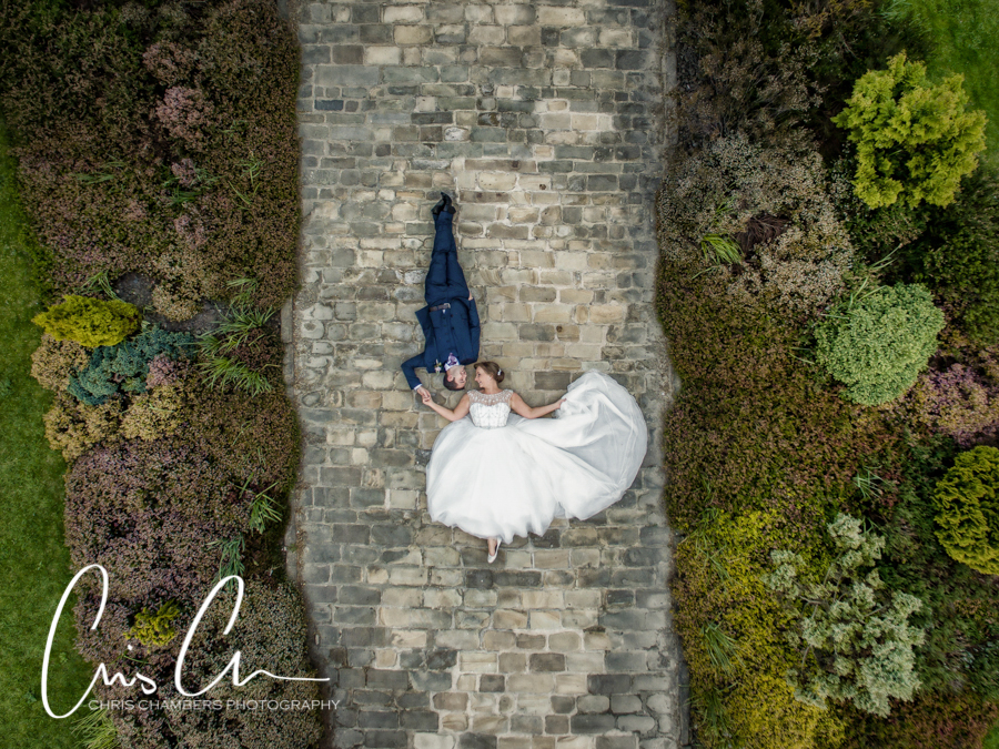 Waterton Park Hotel Wedding Photography in West Yorkshire, Bride and groom lay on the path for a drone wedding photograph