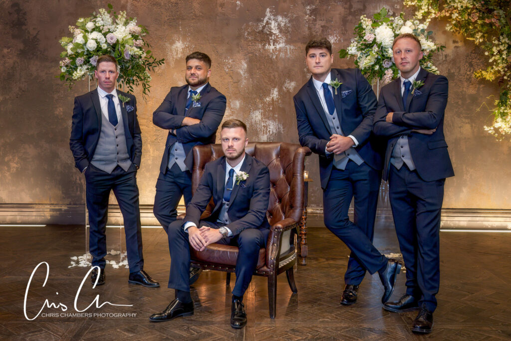 Groomsmen posing in elegant attire at wedding venue.