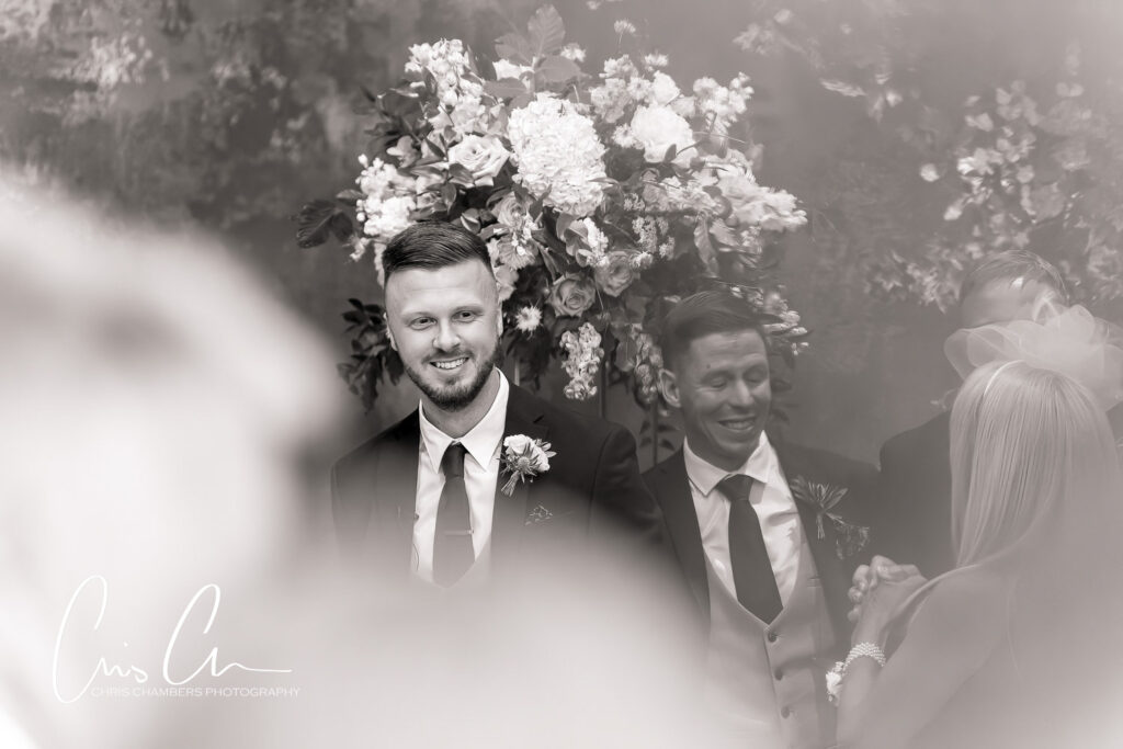 Groom smiling at wedding ceremony with floral backdrop