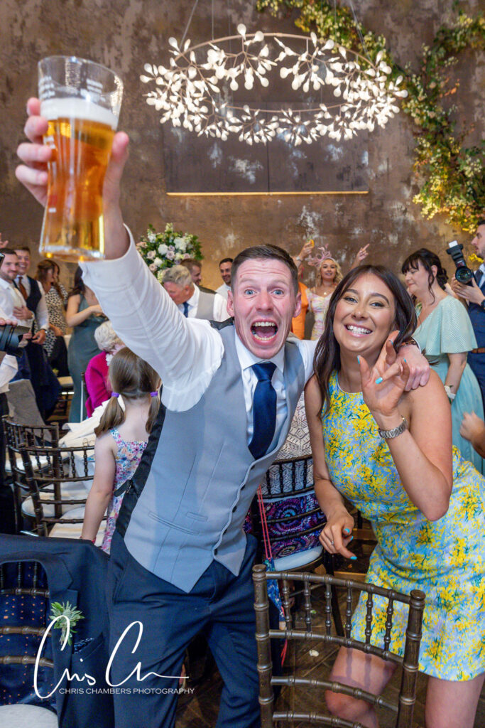 Joyful wedding guests toasting with beer. Manor House Lindley Wedding Photographs