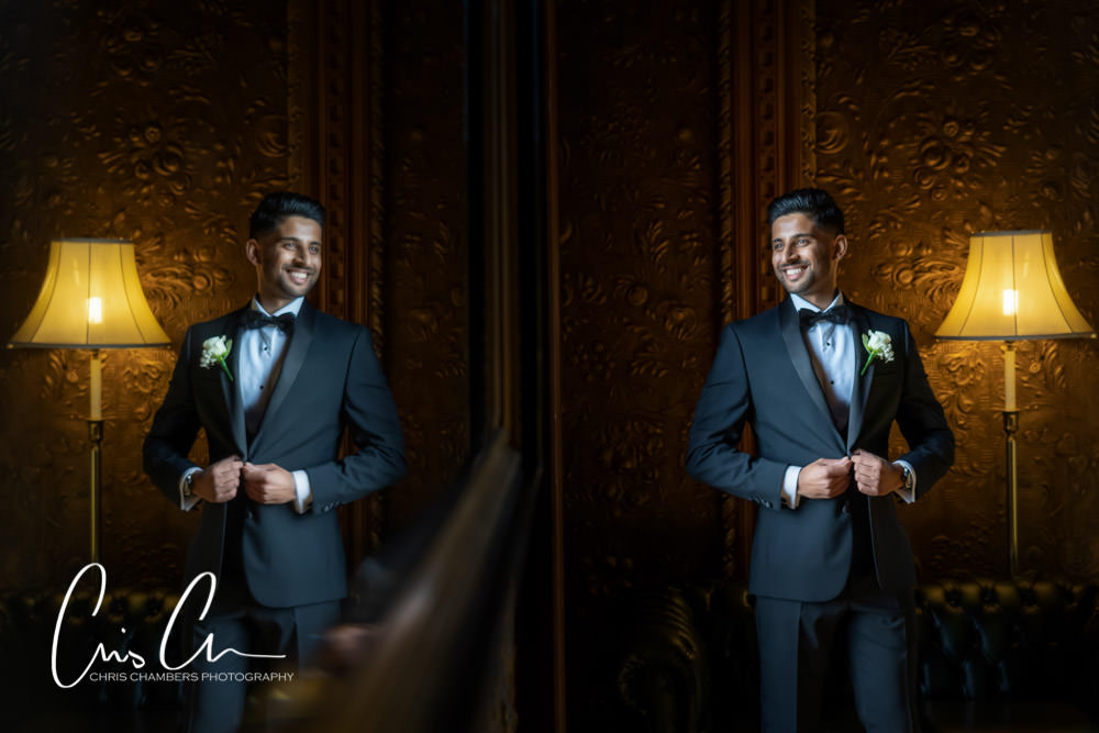 Groom smiling in tuxedo near vintage lamp. Hazlewood Castle Wedding Photography.