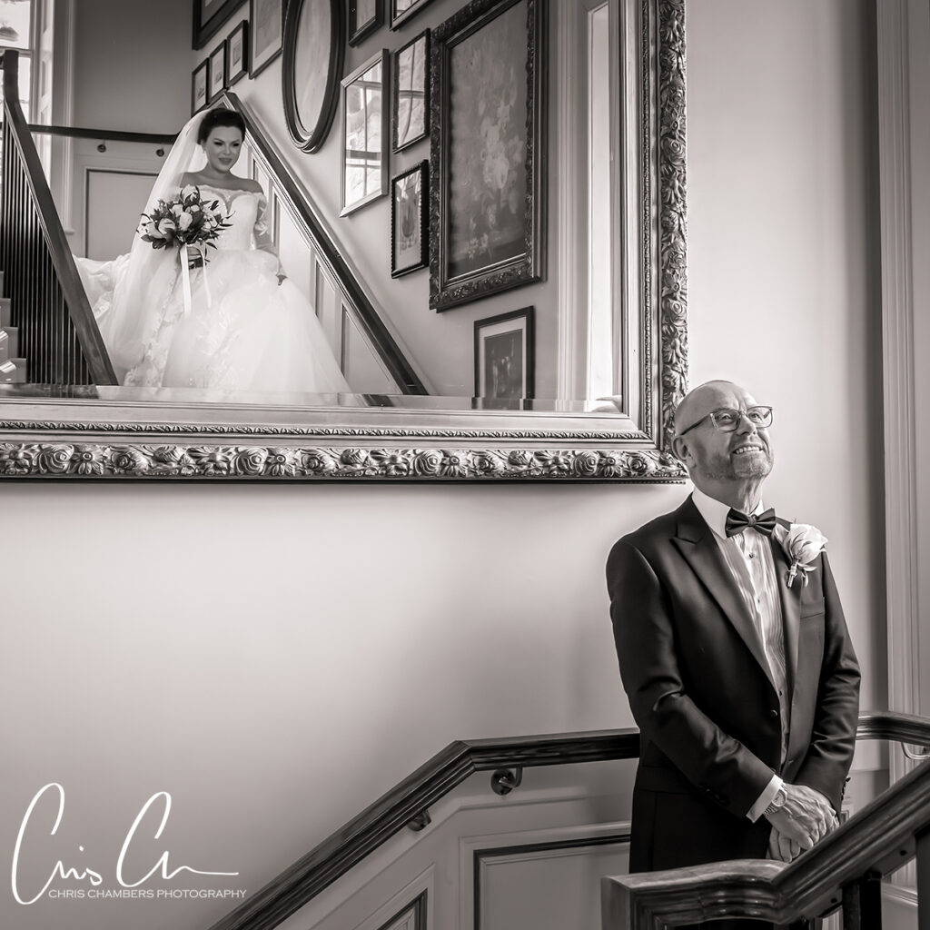 Grantley hall wedding photographer. North Yorkshire wedding venue. Bride descending stairs, man in tuxedo smiling.