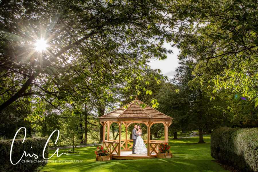 Hazlewood Castle Wedding Photography. Bride and groom in gazebo, sunlit garden wedding.