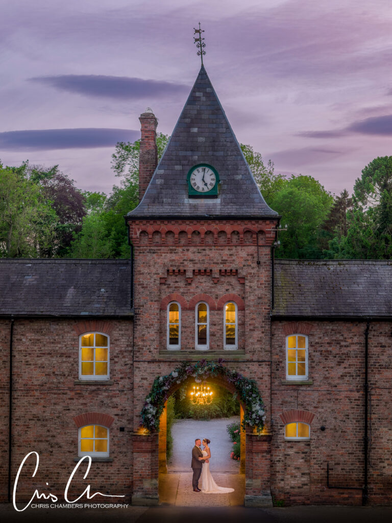 Solberge Hall - bride and groom under the clock tower at twilight. Award winning wedding photography from Chris Chambers